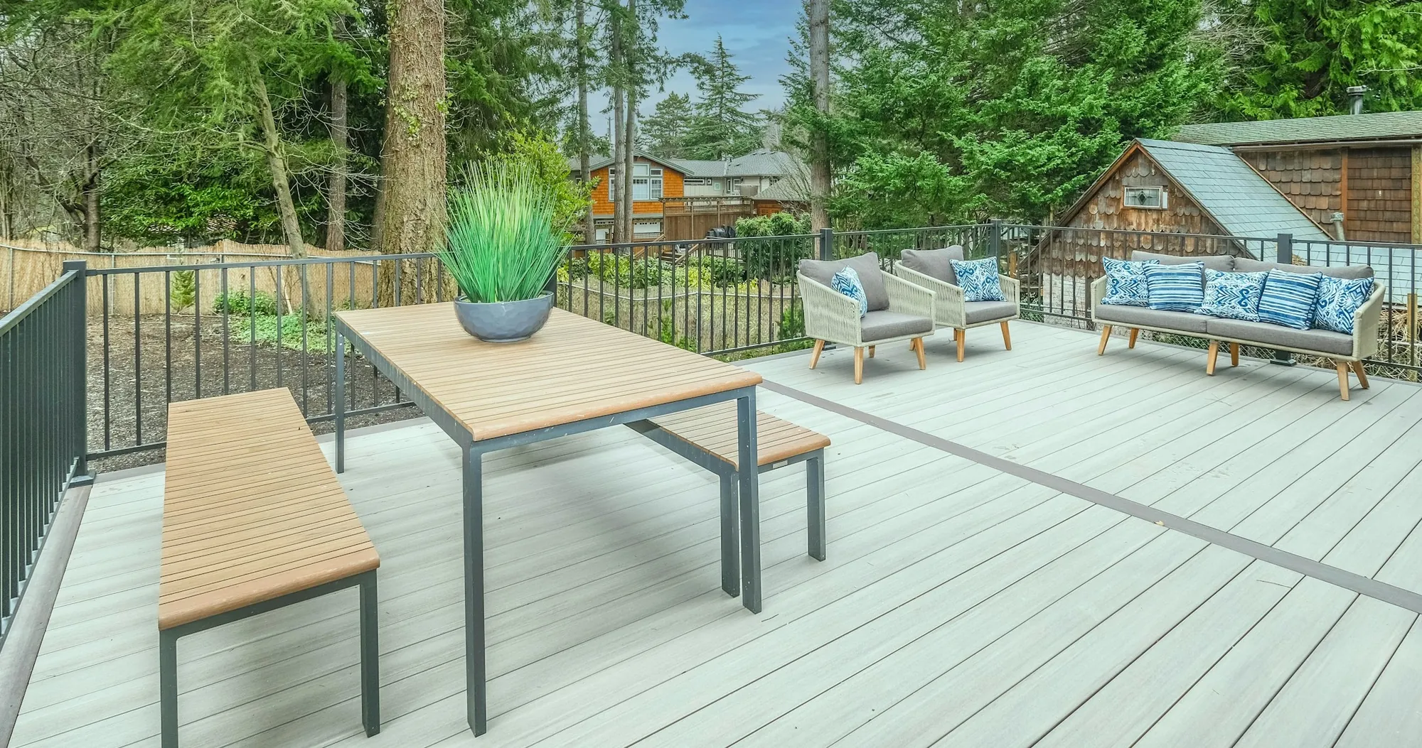 Grey composite deck with a dining table, benches and black railing