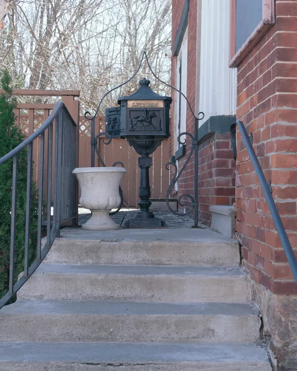 Concrete front steps with an iron railing beside a brick rowhouse